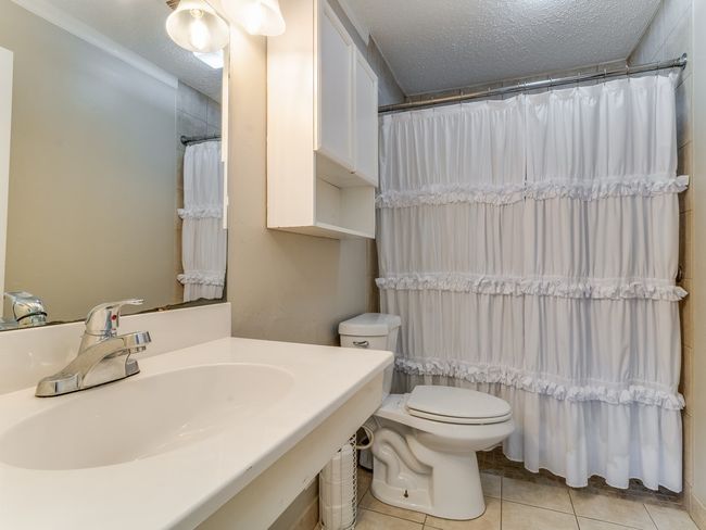 Bathroom featuring tile patterned flooring, vanity, a textured ceiling, and a shower with curtain | Image 16