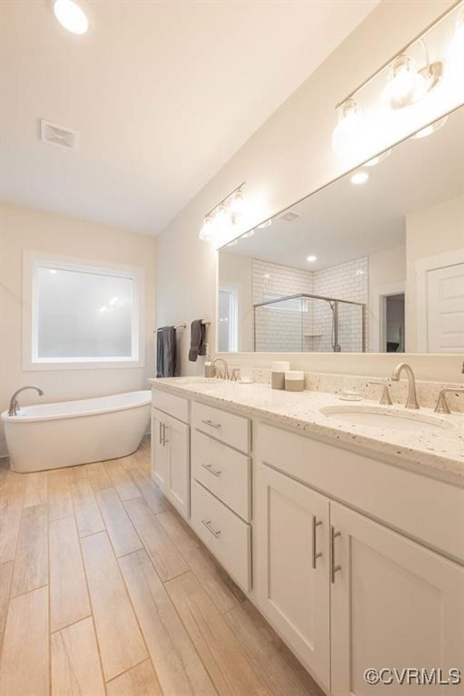 Bathroom with double vanity, a stall shower, wood finished floors, and a freestanding bath | Image 20