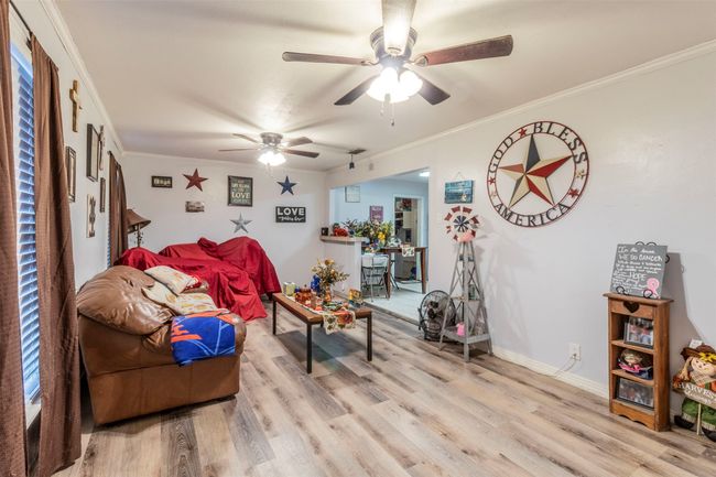 Living room featuring ceiling fan, light wood-style flooring, baseboards, and ornamental molding | Image 7