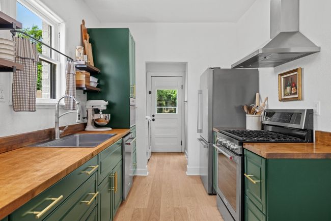 Kitchen with green cabinets, stainless steel appliances, countertops, laundry, door accessing the backyard area | Image 9