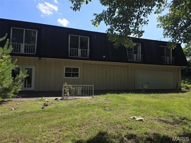 Rear view of property with an attached garage, a lawn, and a balcony | Image 11