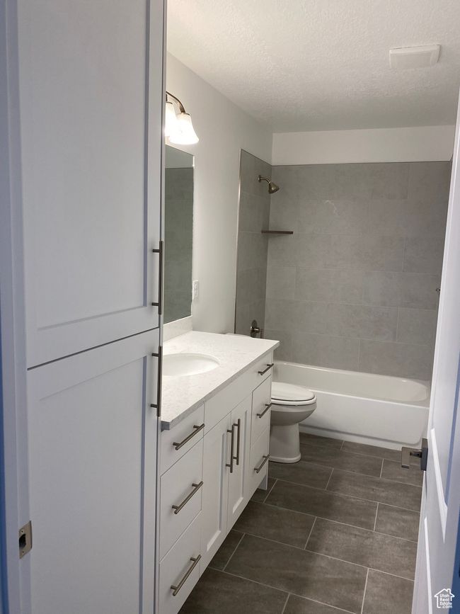 Bathroom with a textured ceiling, toilet, vanity, and shower combination | Image 6