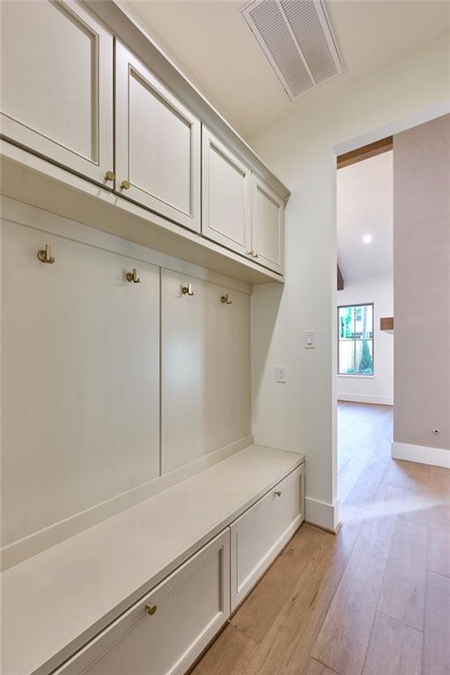 Well-appointed mudroom with built-in storage cabinets, hooks for hanging items, and a bench for convenience. | Image 25