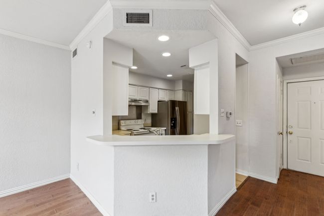 Kitchen with stainless steel refrigerator with ice dispenser, white electric range oven, crown molding, and wood finished floors | Image 15