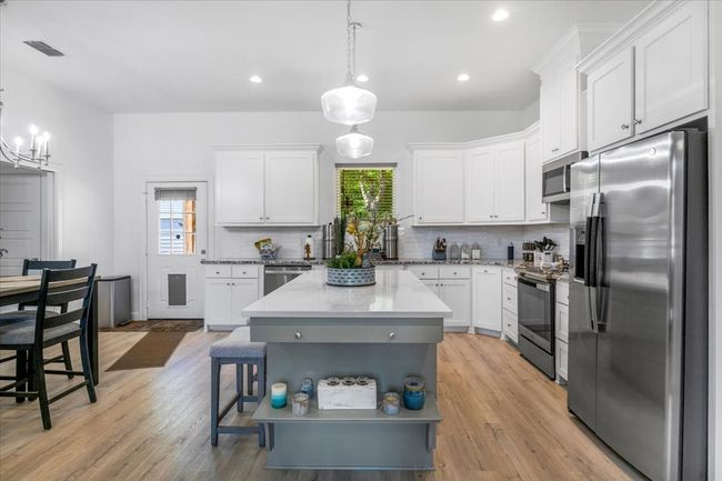 Kitchen featuring backsplash, white cabinets, and appliances with stainless steel finishes | Image 13