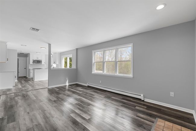 Unfurnished living room with visible vents, dark wood-style floors, baseboard heating, and baseboards | Image 9