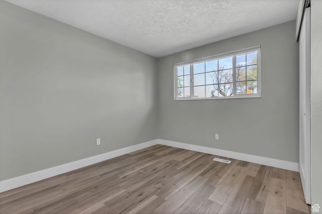 Unfurnished room featuring a textured ceiling, visible vents, wood finished floors, and baseboards | Image 17