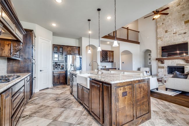 Kitchen featuring appliances with stainless steel finishes, sink, hanging light fixtures, light stone countertops, and a spacious island | Image 13