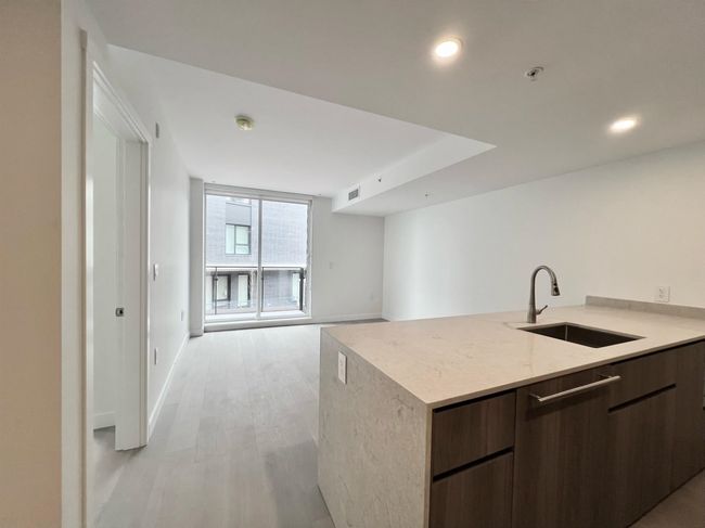 Kitchen with modern cabinets, open floor plan, light wood-style flooring, dark brown cabinetry, and recessed lighting | Image 4