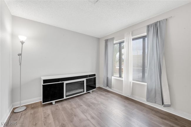 Unfurnished living room featuring a textured ceiling, wood finished floors, and baseboards | Image 16