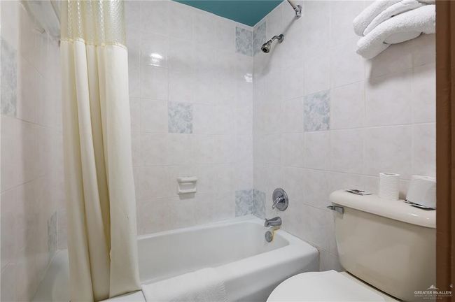 Full bath featuring tile walls, toilet, and shower / tub combo | Image 8