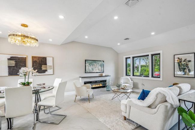 Living room featuring recessed lighting, lofted ceiling, a fireplace, and a chandelier | Image 9