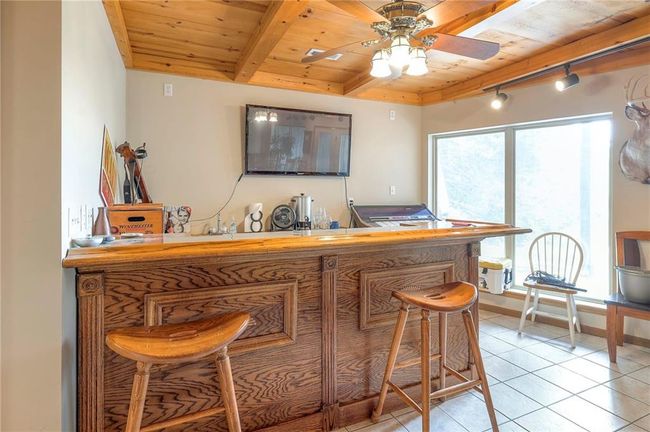 Indoor dry bar with a wooden ceiling with exposed beams, ceiling fan, light tile patterned floors, and track lighting | Image 33
