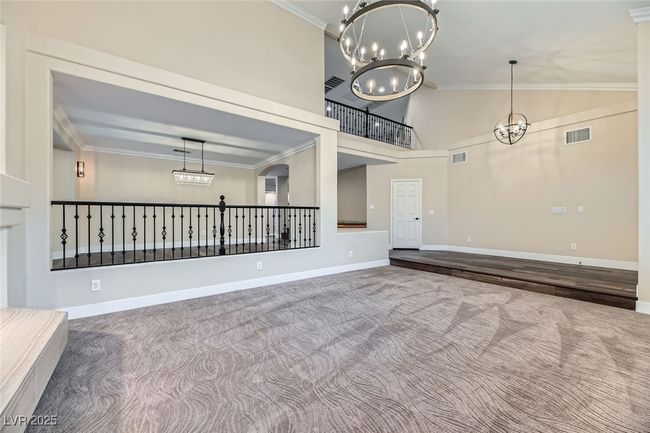 Spare room with carpet, ornamental molding, a chandelier, and a towering ceiling | Image 10