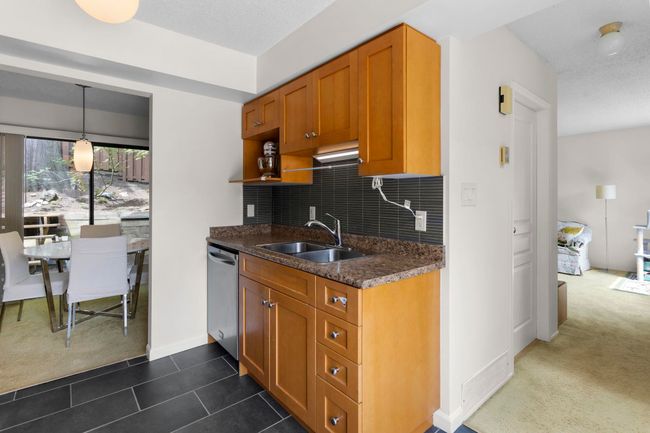 Kitchen with stainless steel dishwasher, dark carpet, brown cabinets, and decorative backsplash | Image 14