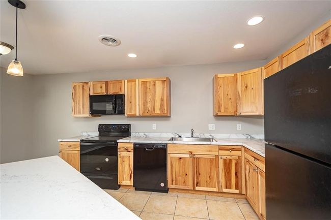 Kitchen with visible vents, light countertops, light tile patterned floors, black appliances, and a sink | Image 17