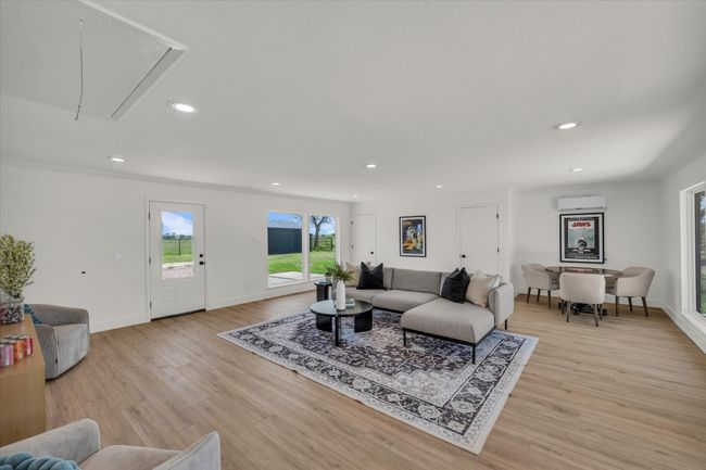 Living room featuring light wood-type flooring, a wall unit AC, attic access, and recessed lighting | Image 24