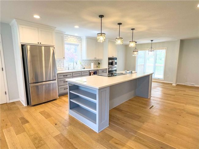 Kitchen with open shelves, white cabinetry, appliances with stainless steel finishes, a sink, and light wood finished floors | Image 7