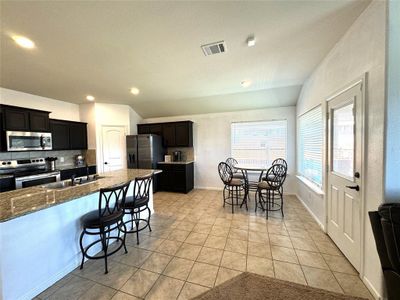 Kitchen with a breakfast bar area, backsplash, stainless steel appliances, sink, and light tile patterned flooring | Image 3