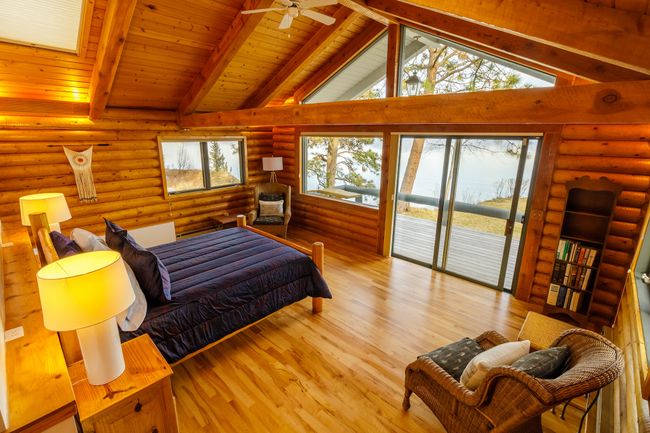 Bedroom featuring beamed ceiling, light hardwood / wood-style flooring, log walls, wooden ceiling, and access to exterior | Image 42