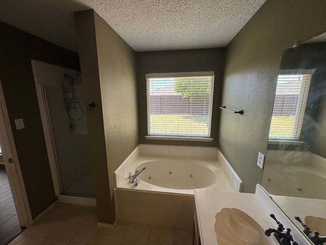 Full bathroom featuring a tub with jets, a textured wall, a shower stall, a textured ceiling, and vanity | Image 11