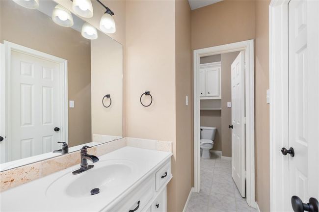 Thoughtfully designed with custom cabinetry and crisp white countertops, this secondary bath combines function with style. Freshly painted in 2024 and finished with clean, modern touches, it’s a welcoming space ideal for guests or everyday family use. | Image 39