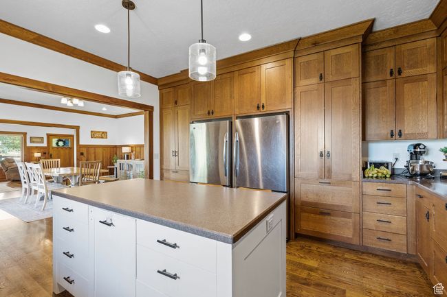 Kitchen with hanging light fixtures, white cabinetry, dark hardwood / wood-style floors, and stainless steel fridge | Image 16