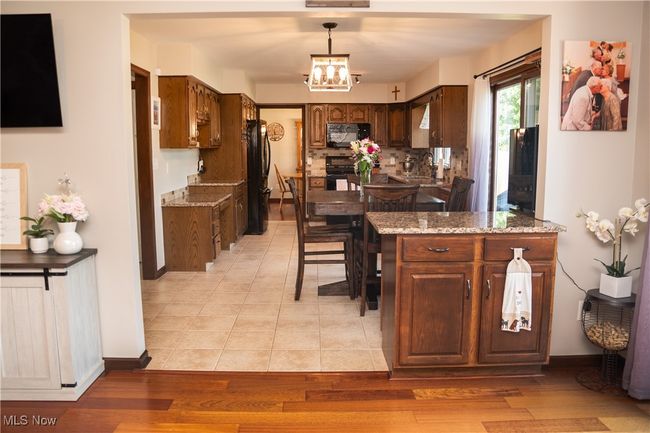 Kitchen featuring black appliances, a chandelier, light stone counters, and decorative light fixtures | Image 26