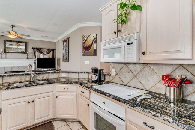 Kitchen featuring appliances, a pot rack, a sink, tasteful backsplash, and light tile patterned flooring | Image 15