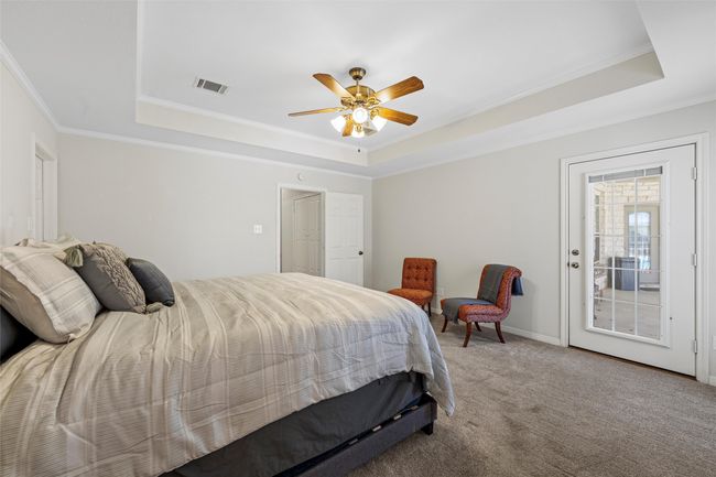 Carpeted bedroom featuring a ceiling fan, ornamental molding, a tray ceiling, and visible vents | Image 18