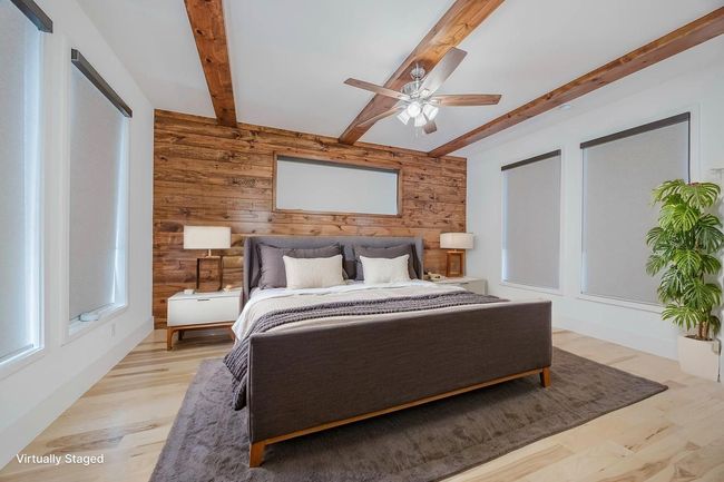 Bedroom featuring wooden walls, beam ceiling, a ceiling fan, and light wood-style floors | Image 17