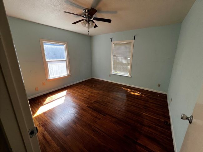 Spare room with wood finished floors, ceiling fan, and baseboards | Image 7