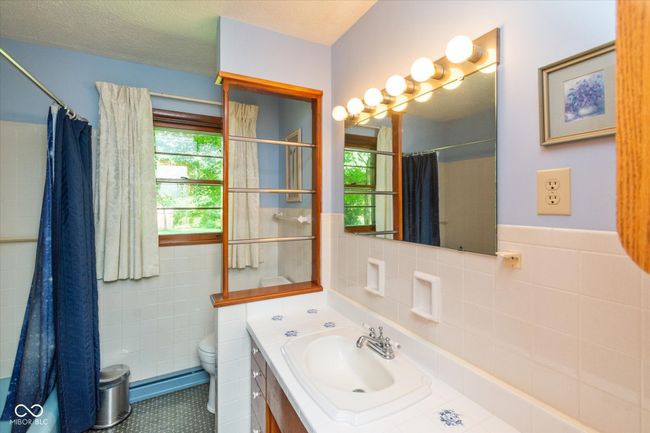 bathroom featuring tile walls, vanity, a shower with curtain, tile patterned flooring, and wainscoting | Image 14