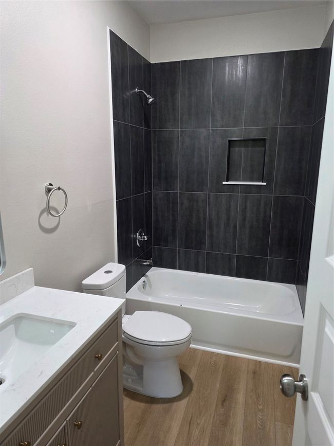 Bathroom featuring wood finished floors, vanity, toilet, and shower / washtub combination | Image 9