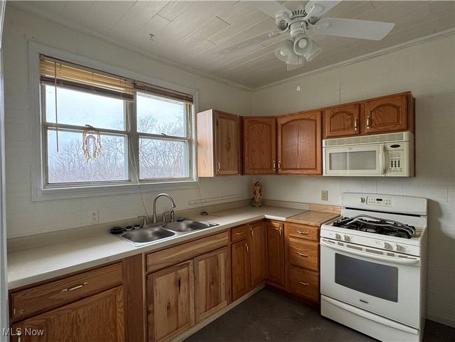 Kitchen featuring sink, white appliances, ornamental molding, and ceiling fan | Image 4