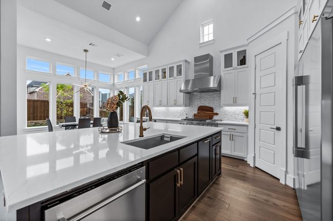Kitchen with appliances with stainless steel finishes, wall chimney range hood, sink, hanging light fixtures, and dark wood-type flooring | Image 11