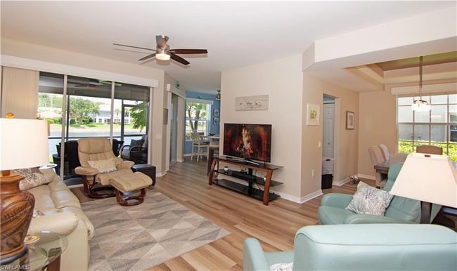 The spacious living room features luxury vinyl plank flooring, a modern ceiling fan and a oversized sliding glass door that leads to the screened lanai. | Image 8