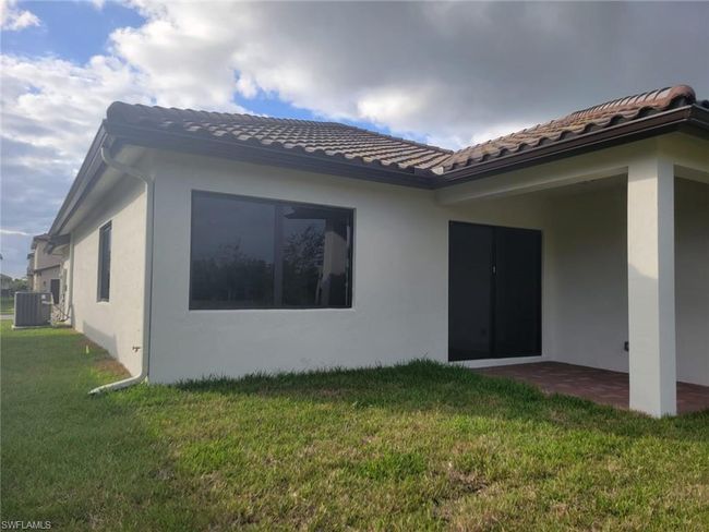 Back of property featuring stucco siding, a lawn, central air condition unit, and a tile roof | Image 29