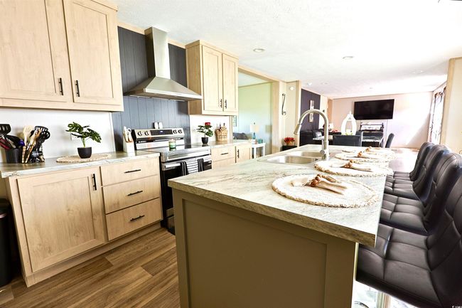 Kitchen with stainless steel appliances, light brown cabinets, wood finished floors, light countertops, and a textured ceiling | Image 5