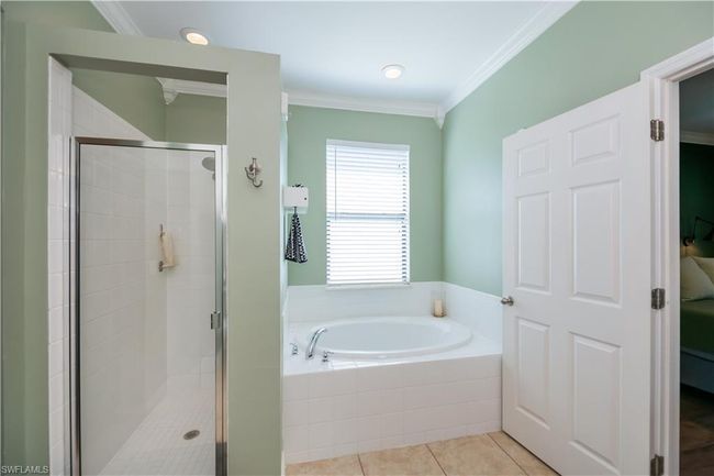 Bathroom with crown molding, tile patterned floors, a shower stall, and a bath | Image 17