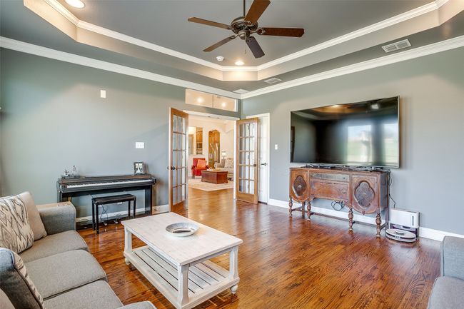 Living room with a raised ceiling, french doors, wood finished floors, and visible vents | Image 22