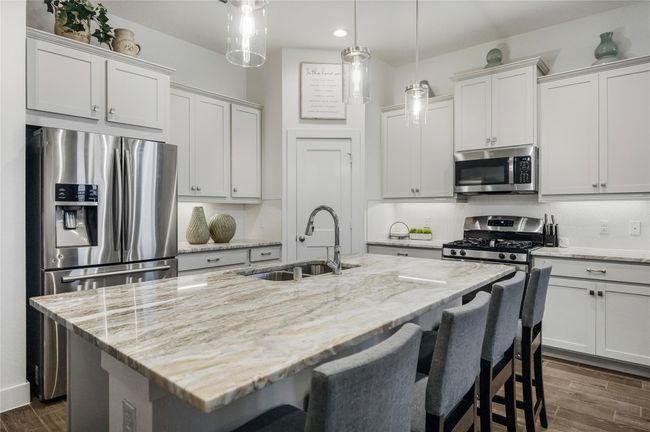 The oversized island doubles as a gathering space, perfect for morning coffee or evening conversation, showcasing beautiful veining that elevates the room’s design. | Image 8