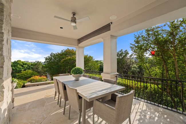 View of patio featuring ceiling fan, outdoor dining area, and view of scattered trees | Image 31
