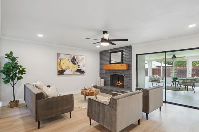 Living room featuring ceiling fan, crown molding, light wood-style flooring, a brick fireplace, and recessed lighting | Image 11