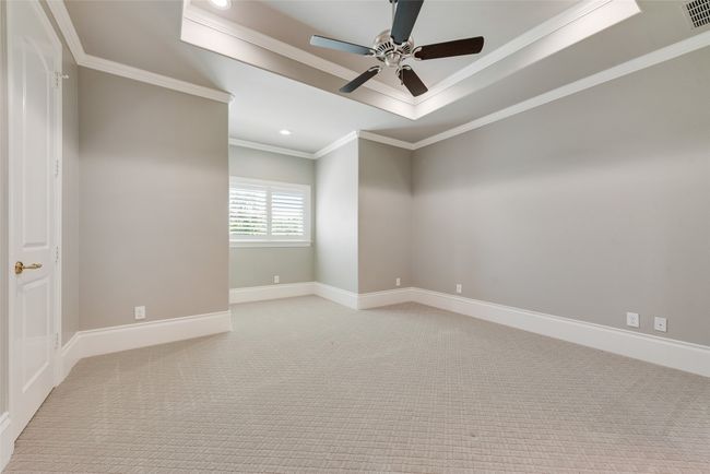 Unfurnished room with light colored carpet, a ceiling fan, crown molding, and a raised ceiling | Image 33
