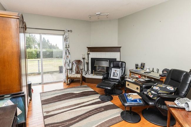 Living area featuring a tiled fireplace and wood finished floors | Image 11