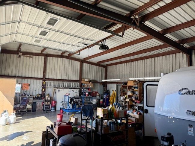 Garage with metal wall, a garage door opener, and a workshop area | Image 11