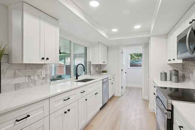 Kitchen featuring appliances with stainless steel finishes, light wood-style floors, backsplash, white cabinets, and recessed lighting | Image 22
