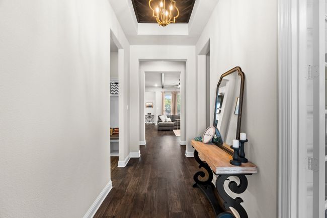 Hallway with dark wood-style flooring, a chandelier, and a tray ceiling | Image 27