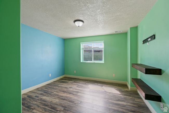 Unfurnished room with a textured ceiling, visible vents, wood finished floors, and baseboards | Image 20